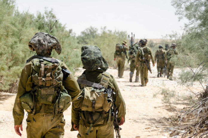 Soldiers walking in formation along a sandy path