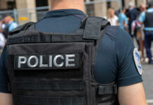 Maui Office Showdown—Armed Candidate Police officer wearing tactical vest in crowd