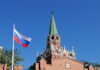 Russian flag and Kremlin tower against a clear blue sky