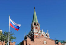 Putin Courts Disillusioned West—No Tests, Fast Track Russian flag and Kremlin tower against a clear blue sky