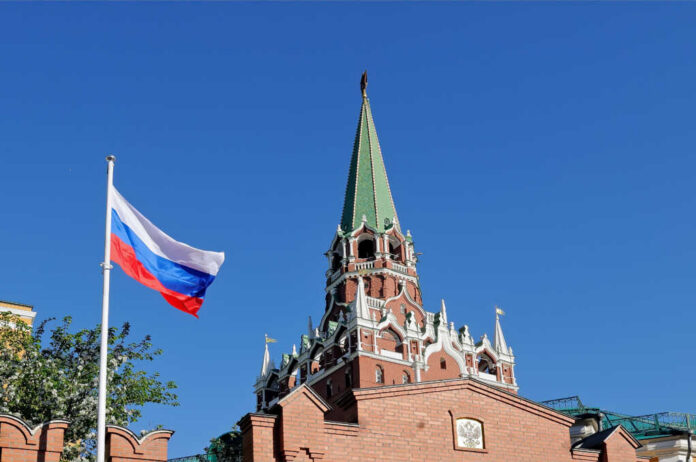 Russian flag and Kremlin tower against a clear blue sky