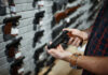 Gun Makers Targeted—The New Lawfare Playbook Person holding a handgun in a gun shop with various firearms displayed on the wall