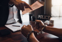 Speech Fight Explodes After Screwdriver Killing A person in handcuffs being confronted by a police officer
