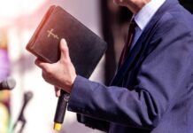 Major Church Vote Sparks Biblical Authority Fight A person in formal attire holding a Bible while speaking