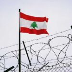 Hezbollah Pause — But For How Long? Lebanese flag waving next to barbed wire fence