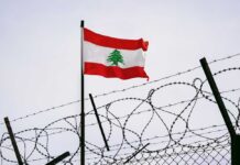 Hezbollah Pause — But For How Long? Lebanese flag waving next to barbed wire fence