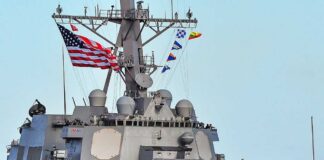 A naval destroyer displaying the American flag and various signal flags