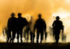 Debt Brake Axed—War Machine Rises Silhouettes of soldiers walking through smoke at sunset