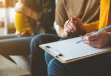Christian Agency Defies LGBTQ Pressure Pregnant woman couple and counselor with clipboard writing