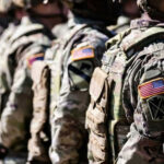Pentagon U-Turn Stuns NATO Watchers Soldiers in camouflage with American flag patches standing