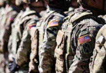 Pentagon U-Turn Stuns NATO Watchers Soldiers in camouflage with American flag patches standing