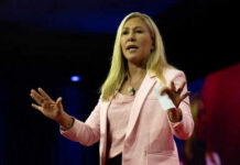 Woman speaking on stage wearing pink blazer