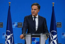 The Ukraine Debate Just Changed Again Man speaking at podium with NATO flags behind him