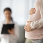 Pregnant person holding their belly during a medical visit