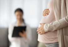 One Number Reveals A Generational Shift Pregnant person holding their belly during a medical visit