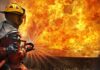 Firefighter spraying water at a large blaze
