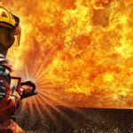 Firefighter spraying water at a large blaze