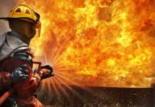 Firefighter spraying water at a large blaze