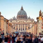 Shock Schism: Excommunications Rock Tradition St. Peter's Basilica viewed from a busy street with crowds