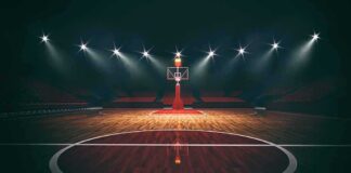 Basketball hoop on an empty indoor court under bright arena lights
