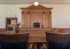 Judge's bench in a traditional courtroom with wooden paneling and empty seats
