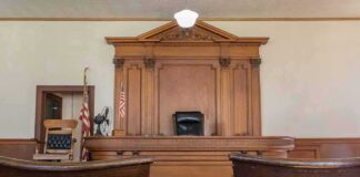 Judge's bench in a traditional courtroom with wooden paneling and empty seats
