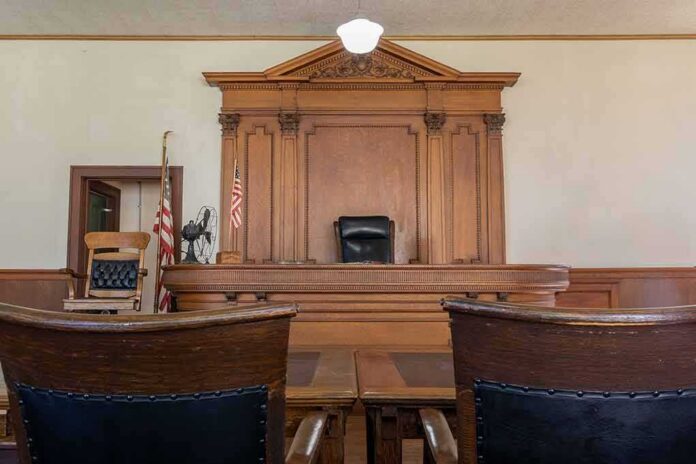 shutterstock_2298224579 Judge's bench in a traditional courtroom with wooden paneling and empty seats