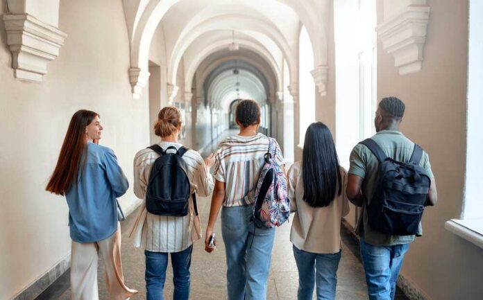 A,Diverse,Group,Of,Five,Students,Happily,Walk,Through,A Group of students walking through a university corridor