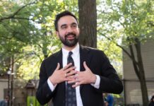Can Socialism And Wall Street Coexist? Man in suit speaking with hands on chest outdoors