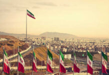 Iran’s Leadership Transition Sends Warning Signals View of Iranian flags with a city and mountains in the background