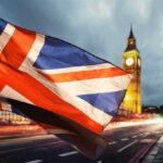 Union Jack flag waving with clock tower in London at dusk