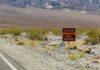 America’s Hottest Town Never Stops Living Warning sign about extreme heat in a rocky desert landscape