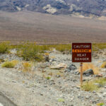 Warning sign about extreme heat in a rocky desert landscape