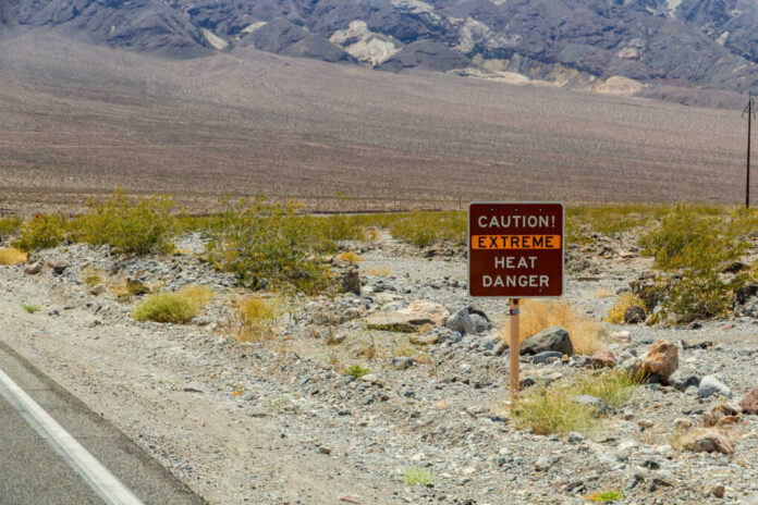 Warning sign about extreme heat in a rocky desert landscape