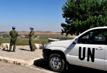 Aid Theft Claims Crumble — So Why Starve Kids? UN peacekeepers stand near a white UN vehicle overlooking rural landscape