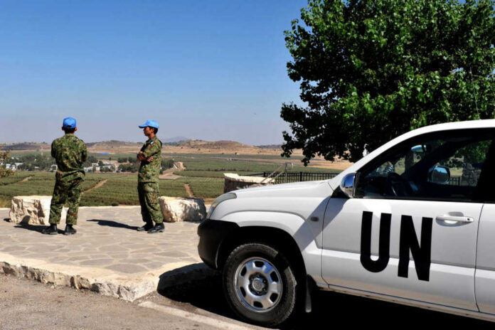 undof-soldiers-examine-the-israeli-syrian-border121577965jpg UN peacekeepers stand near a white UN vehicle overlooking rural landscape