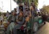 Five Years Later, Was This Really “Security”? Armed men sitting on a pickup truck.