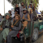 Armed men sitting on a pickup truck.