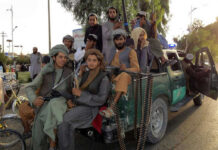 Armed men sitting on a pickup truck.