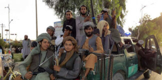 Armed men sitting on a pickup truck.