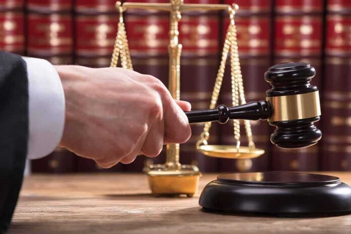Judge's hand holding gavel near scales of justice