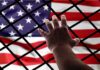 Bill Maher’s Immigration Take Turns Heads Hand reaching through fence toward American flag