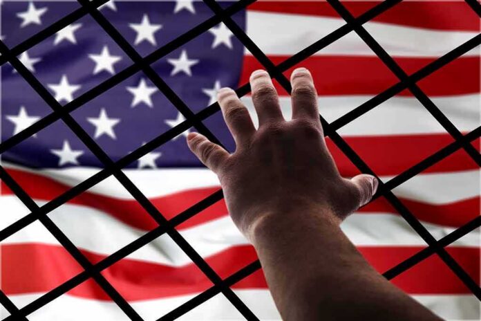 Hand reaching through fence toward American flag
