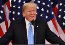 Trump’s ‘Greatest’ Flex Has Everyone Talking Again man at podium with U.S. flags behind him