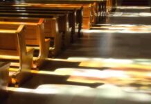 The FBI’s Catholic Controversy Just Got Bigger Wooden church pews with stained glass light on the aisle