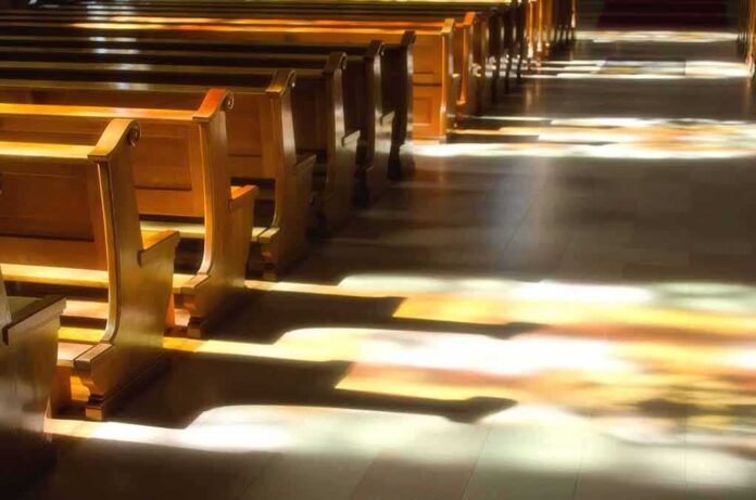 shutterstock_125481890 Wooden church pews with stained glass light on the aisle