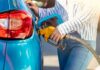 Person refueling a blue car with a yellow gas nozzle