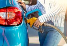 Person refueling a blue car with a yellow gas nozzle
