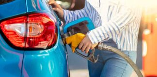 Person refueling a blue car with a yellow gas nozzle