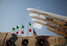 Iran’s Victory Lap Runs Into an Awkward Reality Missile launchers on a military vehicle with flags in the background